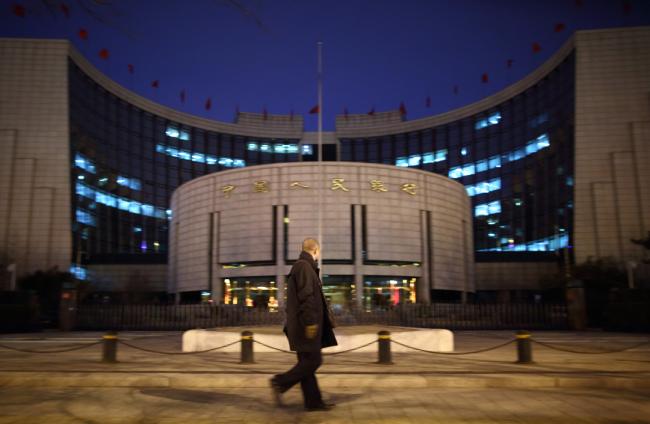 © Bloomberg. A pedestrian walks past the People's Bank Of China (PBOC) headquarters at night in the financial district of Beijing, China, on Monday, March 2, 2015.  Photographer: Tomohiro Ohsumi/Bloomberg