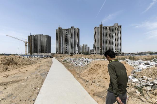 © Bloomberg. A worker walks towards residential buildings under construction in Qingdao, China, on Tuesday, May 8, 2018. China is scheduled to release new home price figures on May 16. 