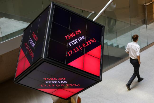 © Bloomberg. An employee walks past FTSE 100 share price information displayed on an illuminated rotating cube in the atrium of the London Stock Exchange Group Plc's offices in London, U.K., on Friday, July 6, 2018. U.K. Prime Minister Theresa May is about to unveil in more detail than ever the kind of divorce from the EU she thinks the country, Parliament and Brussels will accept, with a policy document called a 