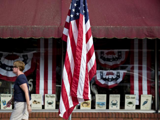 © Bloomberg. An American flag hangs in front of a store on Main Street in Smithfield, Virginia. 