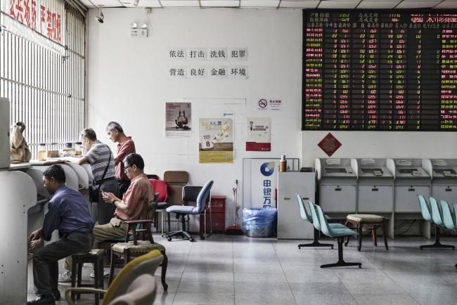 © Bloomberg. Investors sit and stand at a trading terminal near an electronic stock board at a securities brokerage in Shanghai, China, on Friday, June 9, 2017.  Photographer: Qilai Shen/Bloomberg