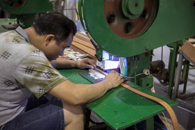 © Bloomberg. An employee manufactures leather belts at the Guangzhou Jinhuamei Leatherware Co. factory in Guangzhou, China, on Wednesday, Sept. 5, 2018. As the trade war between the U.S. and China disrupts the supply of goods and materials across the Pacific Ocean, a vast web of suppliers, distributors, manufacturers and customers that took decades to build is being challenged by tariffs on both shores. Photographer: Giulia Marchi/Bloomberg