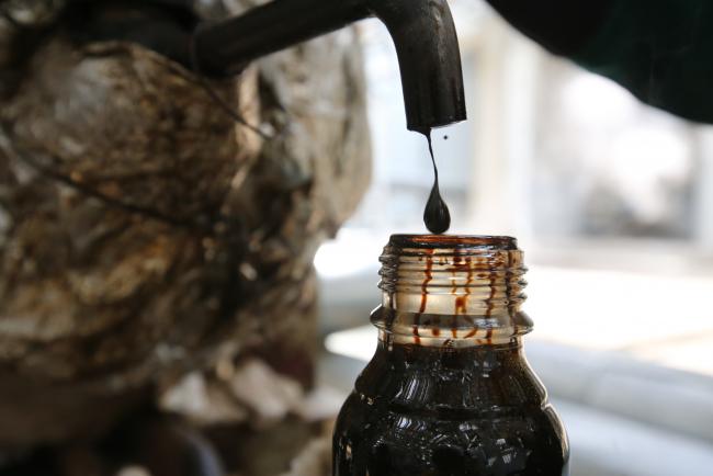 © Bloomberg. A sample of crude oil falls into a bottle for laboratory testing at the 