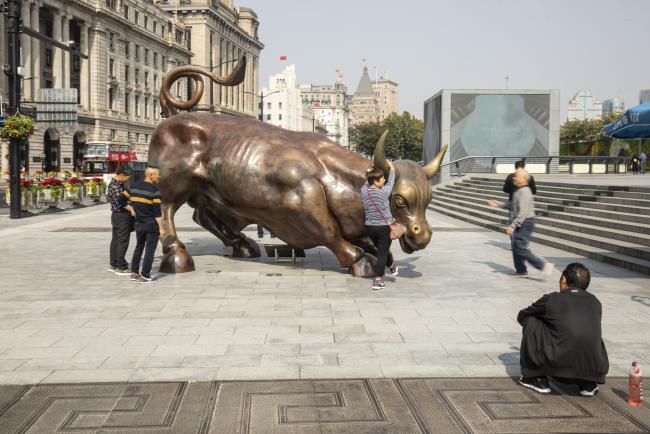 © Bloomberg. People take photographs with the Bund Bull statue in Shanghai, China, on Wednesday, Oct. 24, 2018. Chinese stocks pared an earlier surge, continuing a pattern of wild swings for the equity benchmark. Photographer: Qilai Shen/Bloomberg