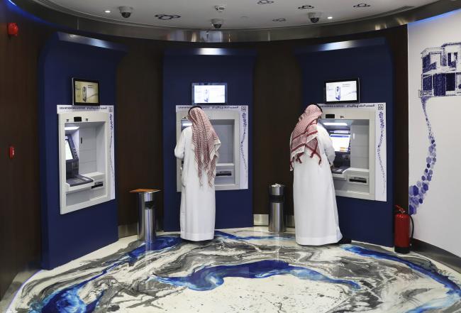 © Bloomberg. Customers use automated teller machines (ATM) inside the Al Rajhi Bank in Riyadh, Saudi Arabia, on Thursday, Dec. 1, 2016.