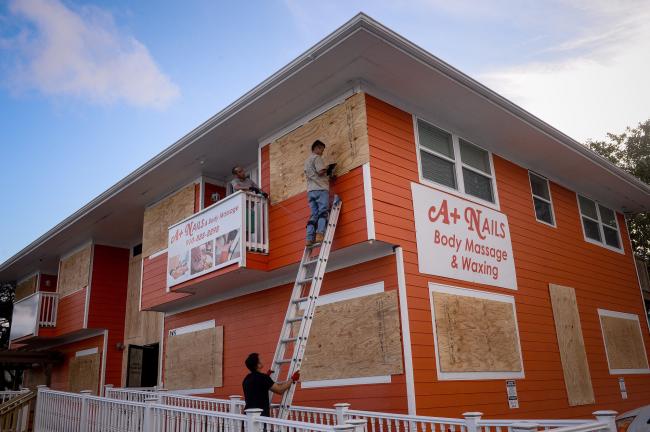 &copy Bloomberg. People secure plywood to windows ahead of Hurricane Florence in North Carolina on Sept. 11. Photographer: Charles Mostoller/Bloomberg 