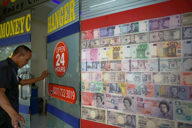 © Bloomberg. A man enters a currency exchange store in Jakarta, Indonesia, on Saturday, Aug. 11, 2018. As Aug. 15's policy decision approaches, Bank Indonesia finds itself under pressure to raise the benchmark rate again even after increasing it by a combined 100 basis points since mid-May to stem a slide in the currency. Photographer: Dimas Ardian/Bloomberg