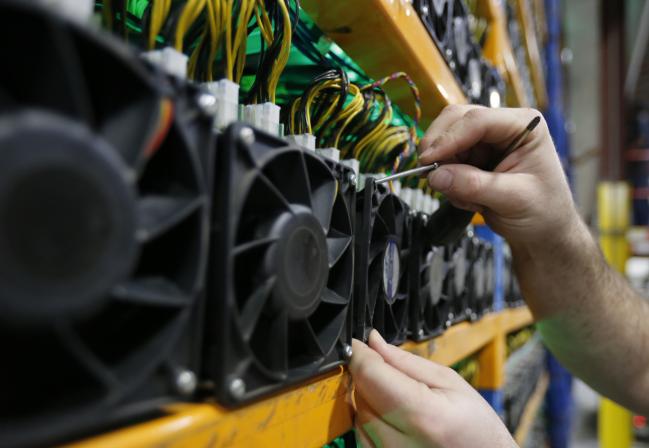 © Bloomberg. An employee changes the fan on a mining machine at the Bitfarms cryptocurrency farming facility in Farnham, Quebec, Canada, on Wednesday, Jan. 24, 2018. Bitfarms says it's making more than $250,000 a day from minting Bitcoin, other virtual currencies and fees at four sites in the province.