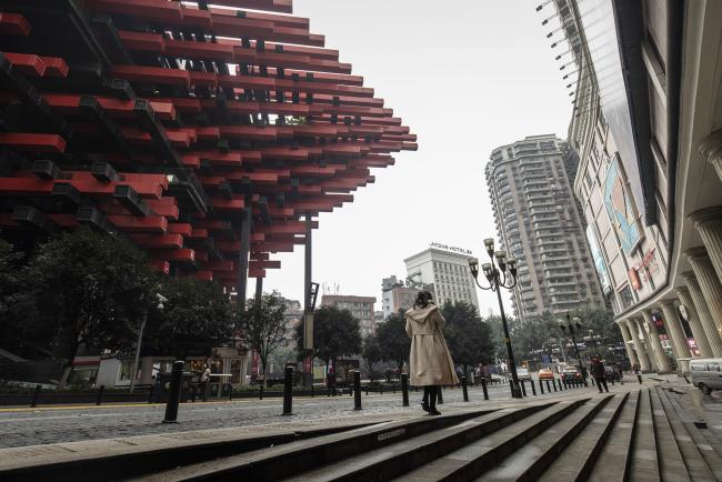 © Bloomberg. A pedestrian walks past the Chongqing Art Gallery, left, in Chongqing. Photographer: Qilai Shen/Bloomberg