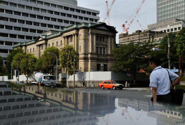 © Bloomberg. Pedestrians walk past the Bank of Japan (BOJ) headquarters in Tokyo, Japan. Photographer: Akio Kon/Bloomberg
