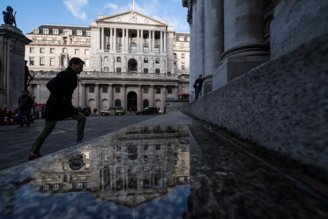 © Bloomberg. A pedestrian walks over a puddle reflecting the Bank of England (BoE) in the City of London, U.K., on Friday, Dec. 15, 2017.  Photographer: Chris J. Ratcliffe/Bloomberg