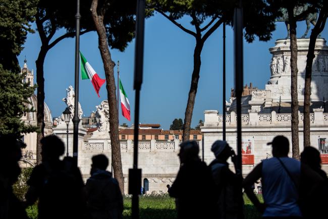 © Bloomberg. The Italian national flag flies near a monument to the unknown soldier in Rome, Italy, on Saturday, Oct. 20, 2018. Italian government bonds, stocks and debt from Europe's other peripheral nations may rally on Monday after a ratings decision by Moody’s Investors Service removed the immediate threat of a downgrade to junk. 