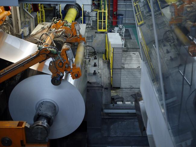 © Bloomberg. An aluminum coil moves through a rolling machine at a manufacturing facility in Alcoa, Tennessee. 