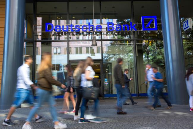 © Bloomberg. Pedestrians walks past a Deutsche Bank AG bank branch in Berlin, Germany, on Tuesday, Sept. 27, 2016. Deutsche Bank AG rose in Frankfurt trading after the German lender agreed to sell its U.K. insurance business for 935 million euros ($1.2 billion) and Chief Executive Officer John Cryan ruled out a capital increase. 