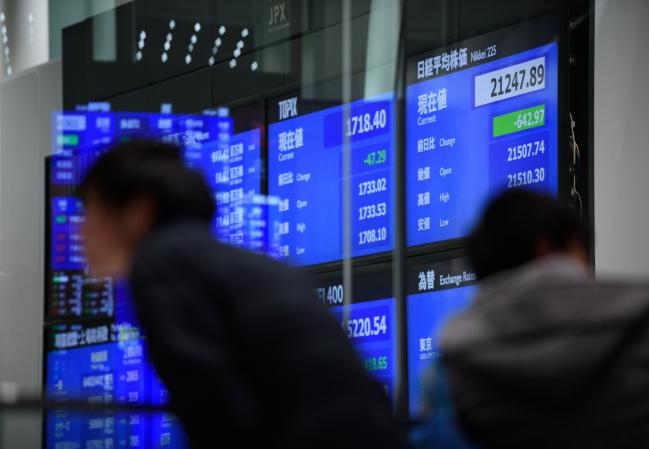 © Bloomberg. Two men stand in front of a screen displaying stock indices at the Tokyo Stock Exchange (TSE), operated by Japan Exchange Group Inc. (JPX), in Tokyo, Japan, on Friday, Feb. 9, 2018. The Topix index headed for its worst week in two years following a meltdown in U.S. equities amid concern rising interest rates will damp economic growth.