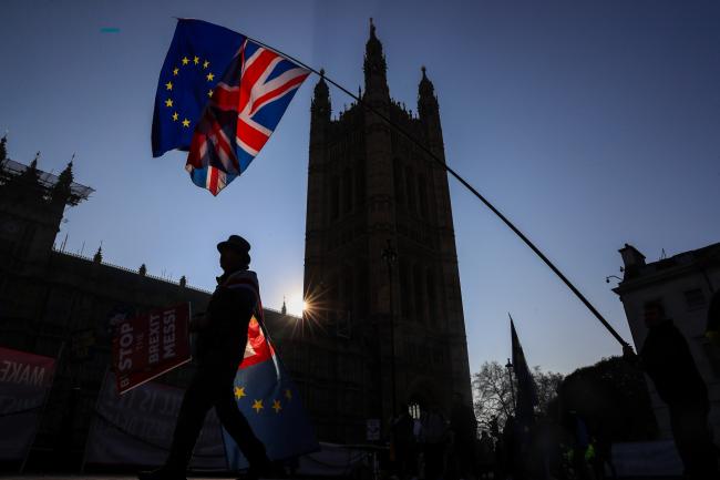 &copy Bloomberg. Anti-Brexit campaigners wave a European Union flag and a Union Jack, also known as a Union Flag, during a protest near the Houses of Parliament in London, U.K., on Wednesday, Feb. 27, 2019.  