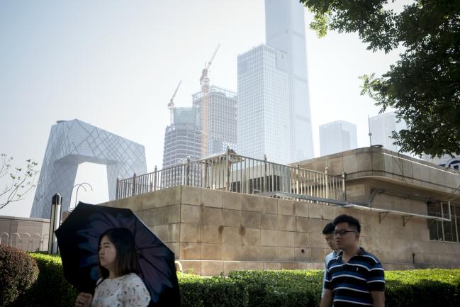 © Bloomberg. Pedestrians walk along a street near the China Central Television (CCTV) headquarters building, left, and other buildings in the central business district in Beijing, China, on Friday, June 1, 2018. The People's Bank of China announced on Friday that it would add debt instruments tied to small-business and the green economy. Photographer: Giulia Marchi/Bloomberg