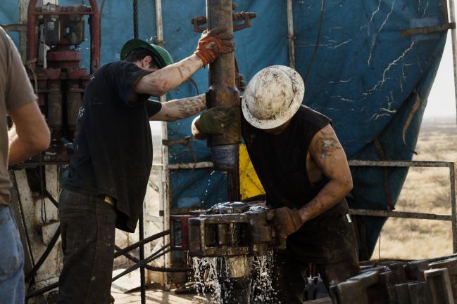 © Bloomberg. Workers connect drill bits and drill collars, used to extract natural petroleum, on Endeavor Energy Resources LP's Big Dog Drilling Rig 22 in the Permian basin outside of Midland, Texas, U.S., on Friday, Dec. 12, 2014. 