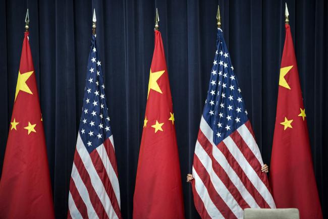 © Bloomberg. A staff member adjusts an American flag before the opening session of the U.S. and China Strategic and Economic Dialogue, in Washington, D.C.