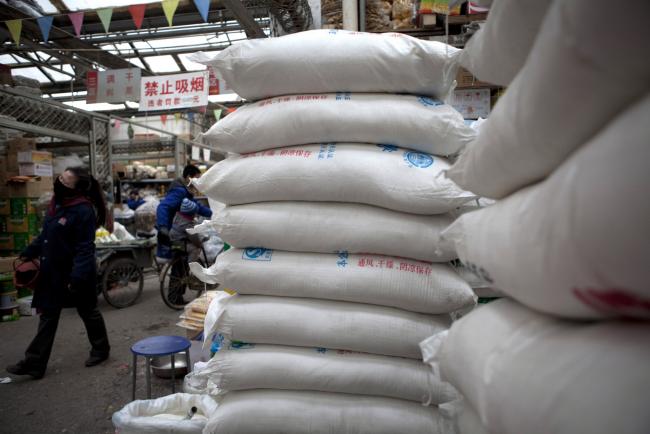 &copy Bloomberg. A pedestrian walks past sacks of sugar in a wholesale market on the outskirts of Beijing, China. Photographer: Adam Sean/Bloomberg