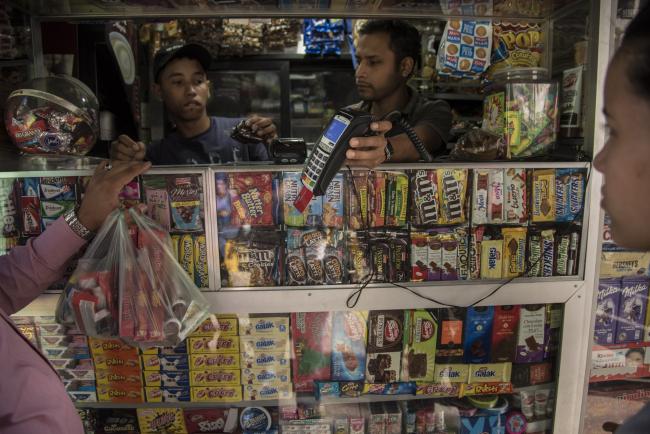 © Bloomberg. A customer pays for candy with a credit card at a stand in the Chacao district of Caracas, Venezuela, on Wednesday, Dec. 6, 2017.