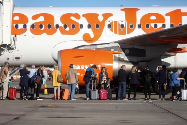 © Bloomberg. Passengers wait to board a passenger aircraft, operated by EasyJet Plc, on the tarmac at London Gatwick airport in Crawley, U.K., on Tuesday, Oct. 11, 2016. London Mayor Sadiq Khan urged U.K. Prime Minister Theresa May to decide quickly to build a new runway at the city's Gatwick Airport, saying it would show that the city is still open for business in the wake of the Brexit vote. 