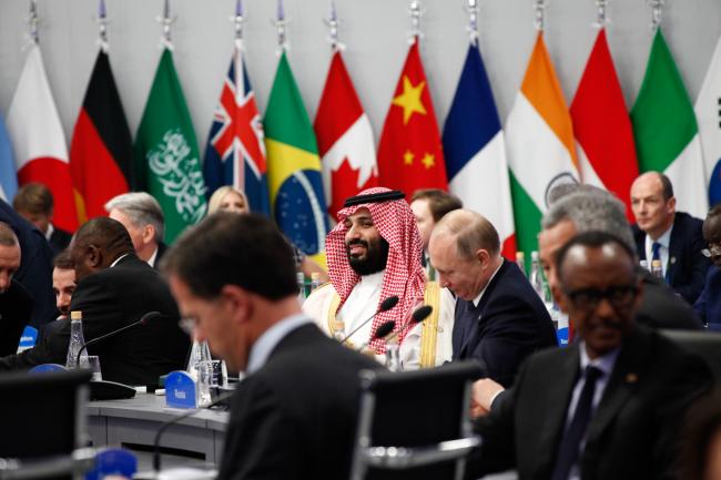 © Bloomberg. Mohammed Bin Salman, Saudi Arabia's crown prince, center, and Vladimir Putin, Russia's president, center right, attend the plenary at the G-20 Leaders' Summit in Buenos Aires on Nov. 30, 2018. 