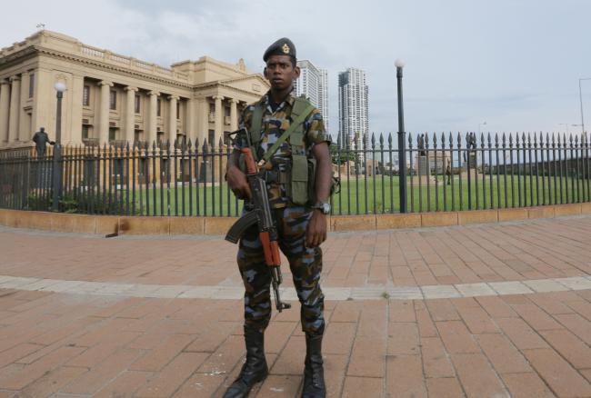 © Bloomberg. A Sri Lankan soldier stands guard outside the Presidential Secretariat building in Colombo, April 22. Photographer: Tharaka Basnayaka/Bloomberg 