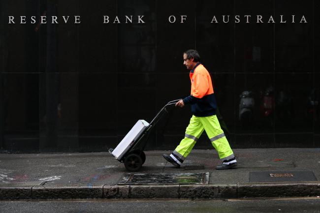 &copy Bloomberg. A pedestrian wheels a trolley past the Reserve Bank of Australia (RBA) headquarters in the central business district of Sydney, Australia, on Thursday, June 21, 2018. Australia is riding out a huge gamble on property. The bet: 27 years of recession-free economic growth—during which Sydney home prices surged fivefold—would continue unabated and allow borrowers to keep servicing their debt. 
