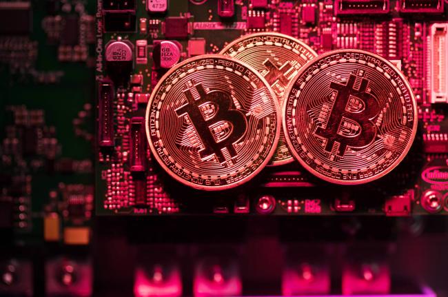 © Bloomberg. Three coins representing Bitcoin cryptocurrency sit on a computer circuit board in this arranged photograph in London, U.K., on Tuesday, Feb. 6, 2018. Cryptocurrencies tracked by Coinmarketcap.com have lost more than $500 billion of market value since early January as governments clamped down, credit-card issuers halted purchases and investors grew increasingly concerned that last year’s meteoric rise in digital assets was unjustified.