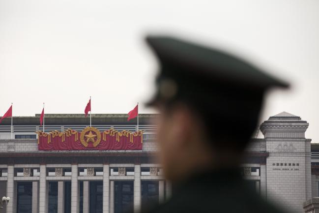 © Bloomberg. A member of the People's Liberation Army (PLA) stands as flags fly above the National Museum of China in Tiananmen Square in Beijing, China, on Wednesday, March 7, 2018. President Xi Jinping is preparing to extend a sweeping government overhaul that would give the Communist Party greater control over everything from financial services to manufacturing to entertainment, two people familiar with the matter told Bloomberg News. Photographer: Giulia Marchi/Bloomberg