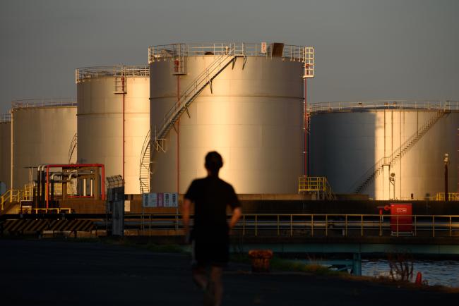 © Bloomberg. A man runs toward tanks in Nagoya, Japan, on Tuesday, July 31, 2018. Japan is scheduled to release trade balance figures for July on Aug. 16. Photographer: Akio Kon/Bloomberg