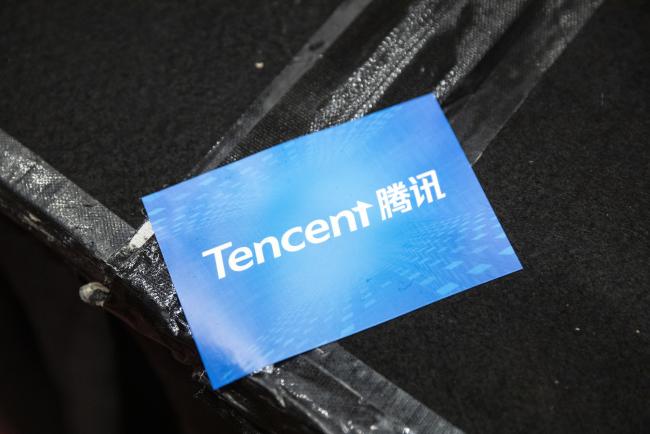 © Bloomberg. A sticker featuring the logo of Tencent Holdings Ltd. is seen during a news conference in Hong Kong, China, on Thursday, March 21, 2019. Tencent posted a quarterly profit that missed analysts’ estimates after it spent heavily on cloud and mobile payments businesses to offset a gaming slowdown. 
