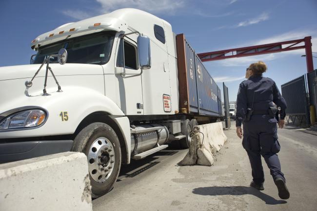 © Bloomberg. A U.S. Customs and Border Protection (CBP) officer walks next to a truck entering from Mexico at the Otay Mesa Cargo Port of Entry in San Diego, California, U.S., on May 23, 2017. The skirmish among House Ways and Means Committee Republicans over a border tax provision resurfaced during a May 24 hearing where Treasury Secretary Steven Mnuchin was testifying on the president's proposed fiscal year 2018 budget. Photographer: David Maung/Bloomberg