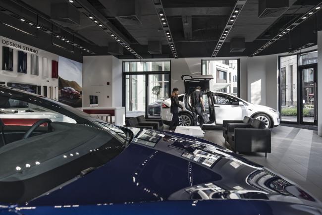 © Bloomberg. An employee assists a customer as he looks at a Tesla Inc. Model S electric vehicle on display at the company's showroom in Shanghai. Photographer: Qilai Shen/Bloomberg