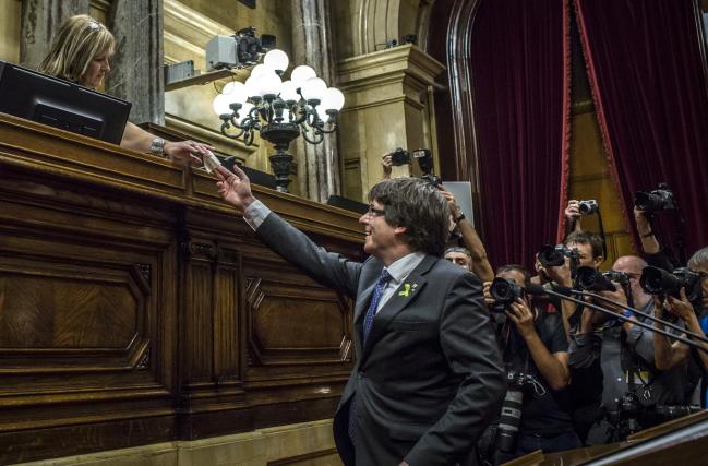 © Bloomberg. Carles Puigdemont, Catalonia's president, hands over his ballot paper during a vote on Catalan independence at the Catalan parliament in Barcelona, Spain, on Friday, Oct. 27, 2017. Catalonia’s tumultuous push for independence is on a knife edge after separatists turned on Puigdemont on Thursday when he was moments away from capitulating to pressure from Spain.