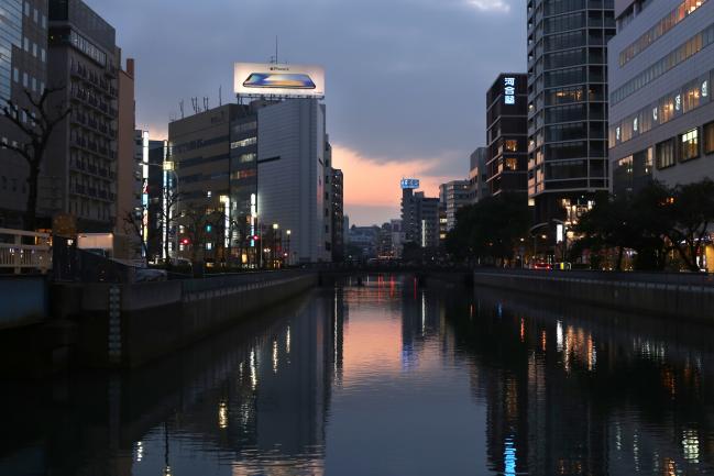 © Bloomberg. An advertisement for the Apple Inc. iPhone X smartphone is displayed atop a commercial building standing near the Katabira River in Yokohama, Japan, on Saturday, Feb. 3, 2018. Japan’s economy expanded for an eighth quarter, with its gross domestic product (GDP) grew at an annualized rate of 0.5 percent in the three months ended Dec. 31, but the pace of growth fell sharply and missed expectations. Photographer: Takaaki Iwabu/Bloomberg