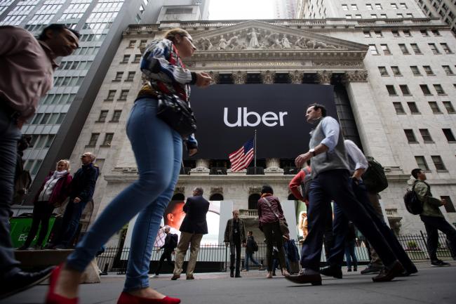 © Bloomberg. Pedestrians pass in front of the New York Stock Exchange (NYSE) during Uber Inc.'s initial public offering (IPO) in New York, U.S., on Friday, May 10, 2019. The No. 1 ride-hailing company's shares will start trading on the New York Stock Exchange after it raised $8.1 billion in the biggest U.S. IPO since 2014, pricing shares at $45 each. Photographer: Michael Nagle/Bloomberg