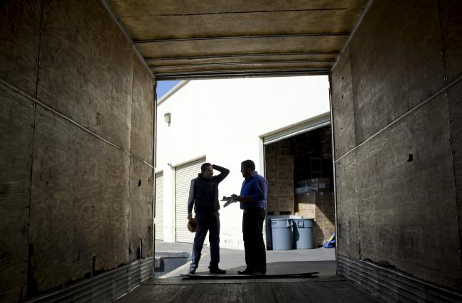 © Bloomberg. Mexican employees speak in the entrance to a trailer truck at the Grupo Behr warehouse in San Diego, California, U.S., on Friday, Oct. 28, 2011. Grupo Behr, which is a subdivision of Grupo Logix, has a permit pending with the U.S. government that would allow the company to begin long haul cargo transport into the U.S., a provision of North American Free Trade Agreement (NAFTA) that had been blocked for years, but was recently approved by President Obama. 