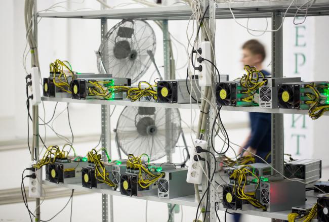 © Bloomberg. An employee passes power supply units and cooling fans linked to cryptocurrency mining machines at the SberBit mining 'hotel' in Moscow, Russia, on Saturday, Dec. 9, 2017. Futures on the world’s most popular cryptocurrency surged as much as 26 percent in their debut session on Cboe Global Markets Inc.'s exchange, triggering two temporary trading halts designed to calm the market.