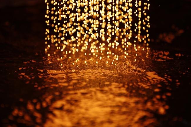 © Bloomberg. Molten gold hits the surface of the water to cool and produce gold casting grain during the refining process. Photographer: Stefan Wermuth/Bloomberg