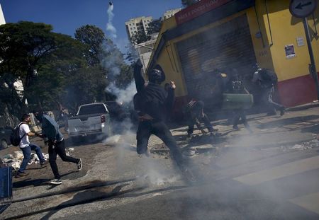 © Reuters. A demonstrator throws a tear gas bomb after military police shot at demonstrators during a protest against the 2014 World Cup, in Sao Paulo