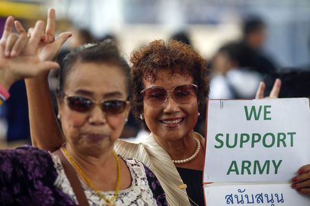 © Reuters. Supporters of the military gesture as they hold up a sign during a reconciliation event organized by the military at a shopping mall in Bangkok