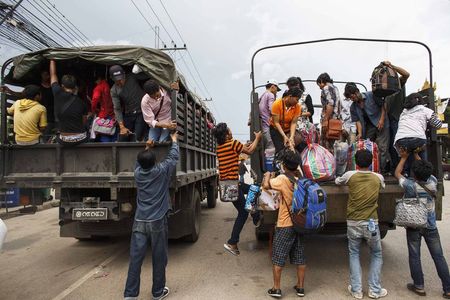 © Reuters. Cambodian workers ride on military trucks as they prepare to cross Thai-Cambodia border at Aranyaprathet in Sa Kaew