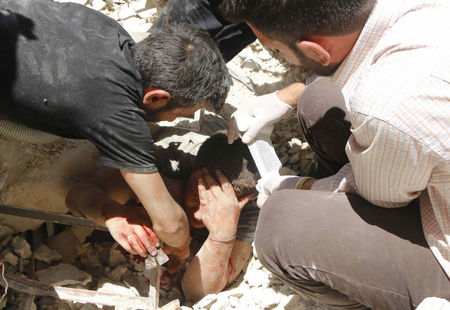 © Reuters. A man tries to pull a casualty from under the rubble of collapsed buildings at a site hit by what activists said was a barrel bomb dropped by forces loyal to Syria's President al-Assad in Aleppo