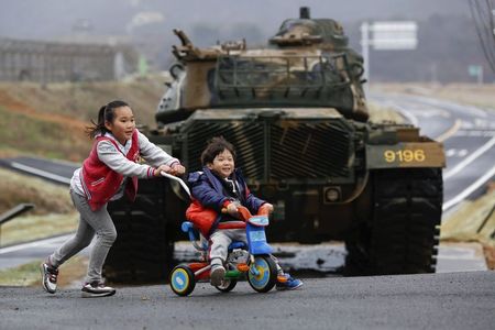 © Reuters. File photo of children playing in front of tank on island of Baengnyeong, which lies on South Korean side of Northern Limit Line, in Yellow Sea