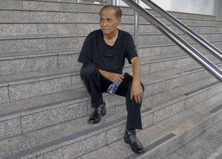 © Reuters. Chalad Vorachat, a retired navy lieutenant and serial hunger striker, sits on the steps of the criminal court in Bangkok