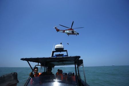 © Reuters. A Malaysia Maritime helicopter is seen in the air during a search and rescue for the suspected illegal Indonesian immigrants, off Malaysia's western coast