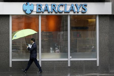 © Reuters. A man shelters under umbrellas as he walks past a Barclays branch in central London