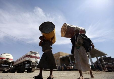 © Reuters. Farmers carry barrels at a fuel station during a diesel shortage in Sanaa